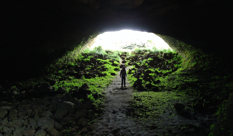 person standing in cave mouth