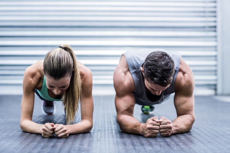 Front view of a muscular couple doing planking exercises
