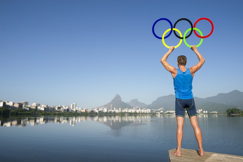 Athlete holding Olympic rings stands on the shore of Lagoa Rodrigo de Freitas lagoon, a venue for the Summer Games