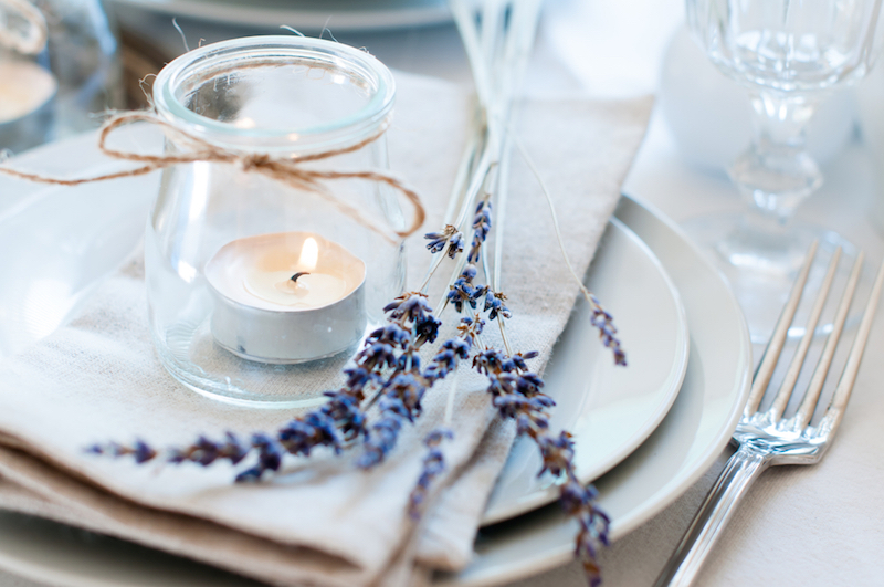 dining table setting at provence style with candles lavender vintage crockery and cutlery closeup