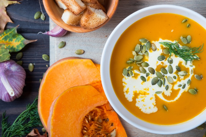 Pumpkin soup among autumn leaves on a wooden table