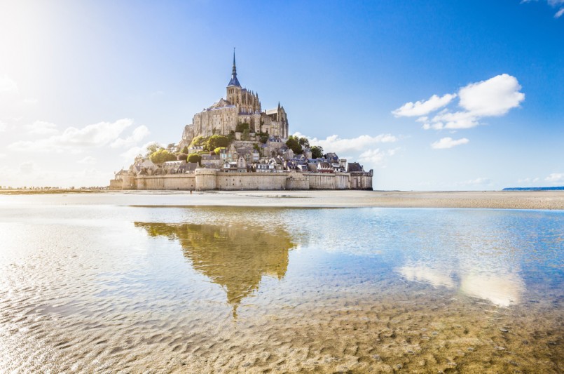 Panoramic view of famous historic Le Mont Saint-Michel tidal island on a sunny day with blue sky and clouds in summer, Normandy, northern France